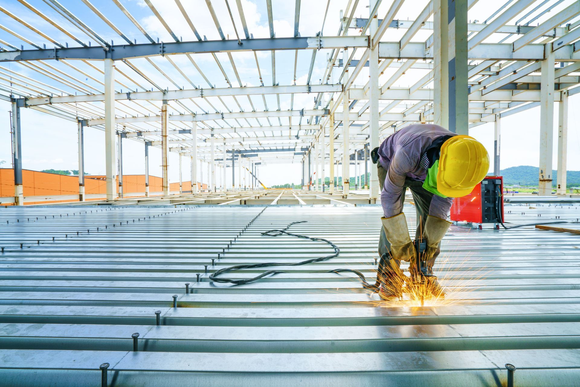 a construction worker welding metal beams inside a large steel framework structure. a construction worker welding metal beams inside a large steel framework structure.