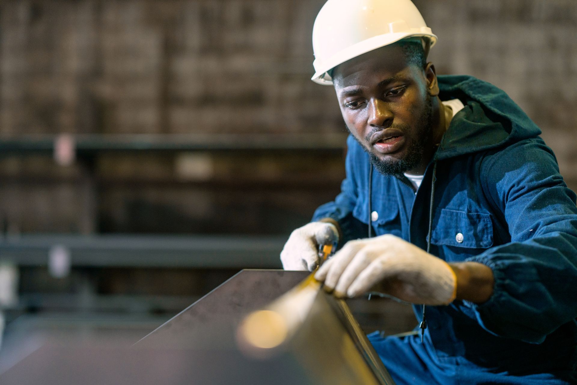A worker is measuring the length of a piece of steel.