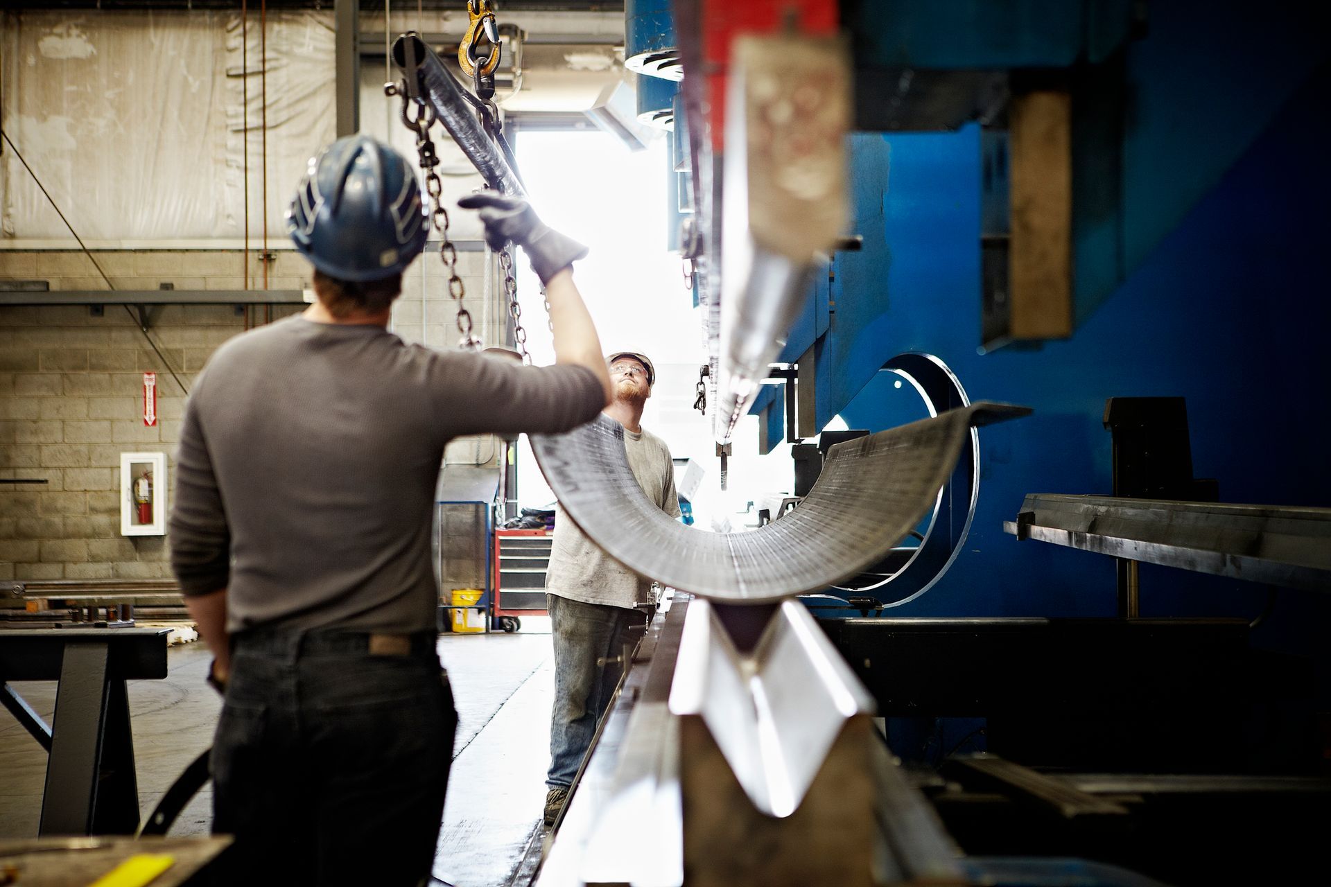 Two male professional workers adjusting position of steel in large brake press. Two male professional workers adjusting position of steel in large brake press.