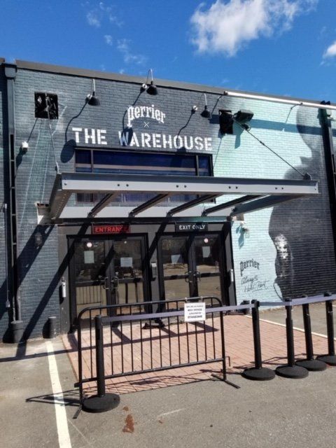 Perrier The Warehouse exterior with entrance doors, black facade, and security barriers.