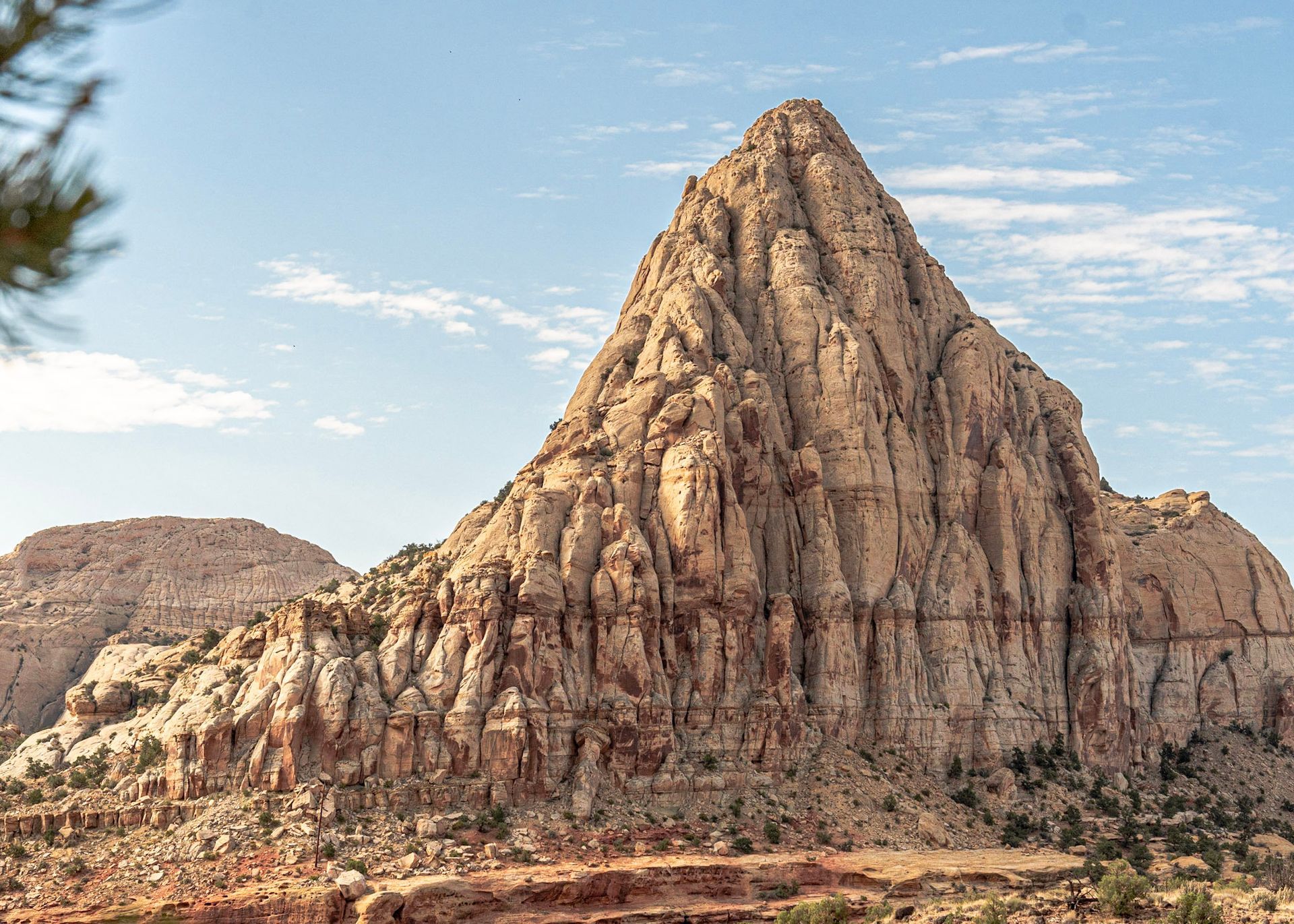 a large rocky mountain in the desert with a blue sky in the background .