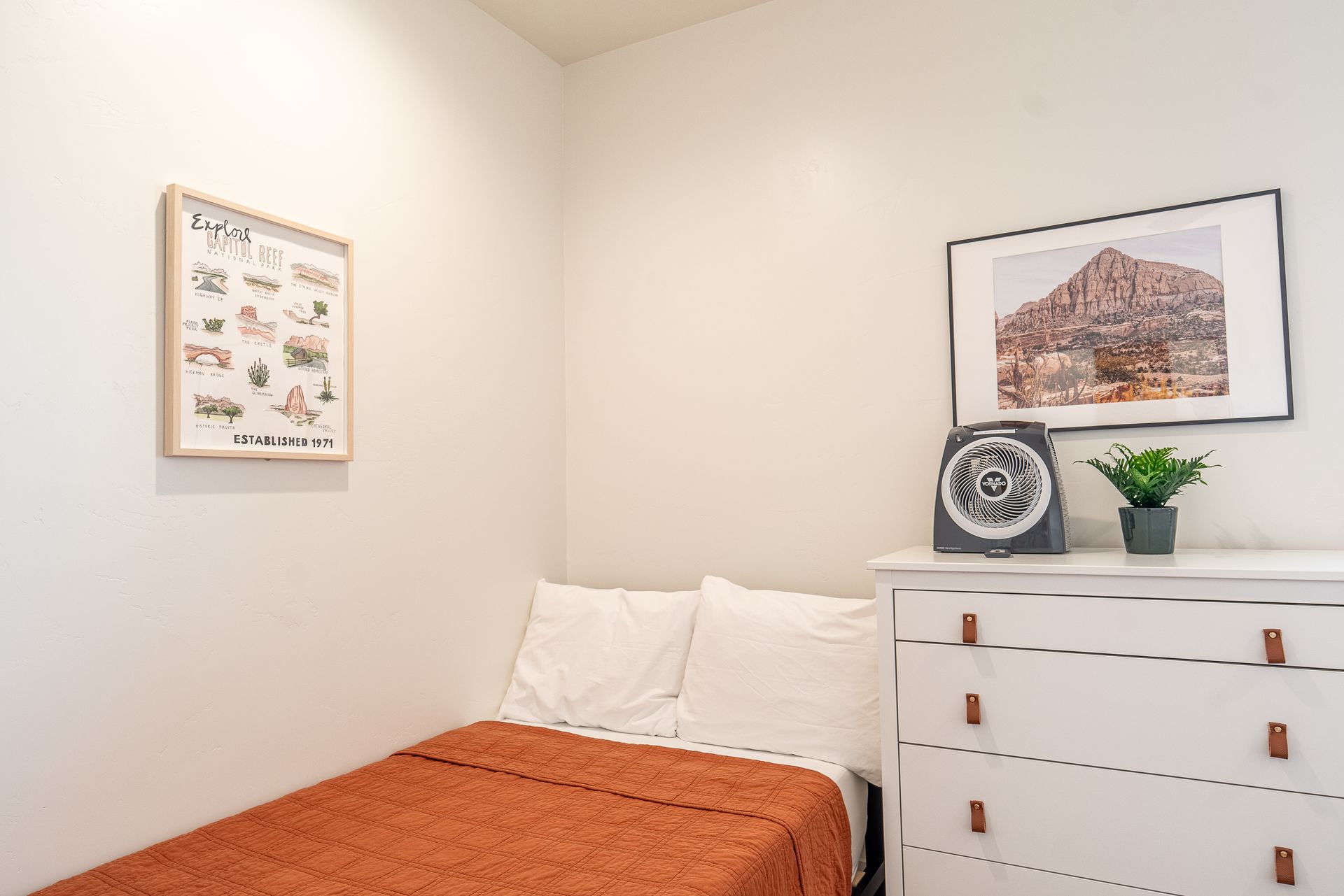 a bedroom with a bed , dresser , and picture on the wall .