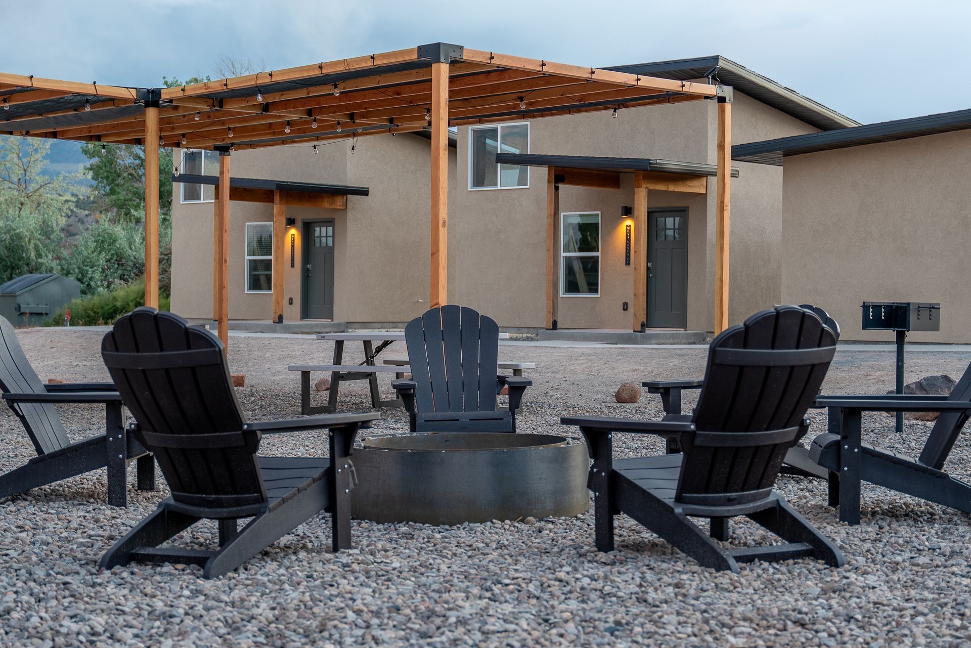 A group of chairs are sitting around a fire pit in front of a house.