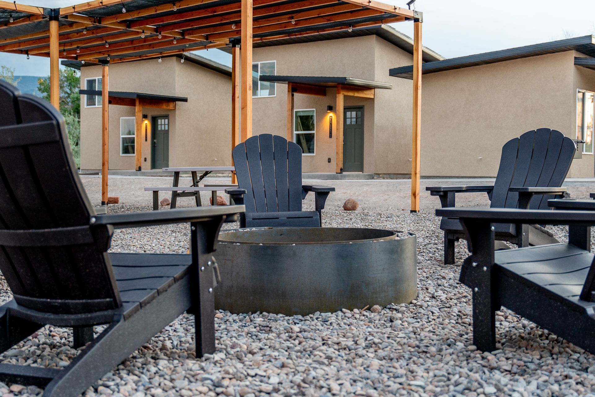 A group of chairs are sitting around a fire pit in front of a house.