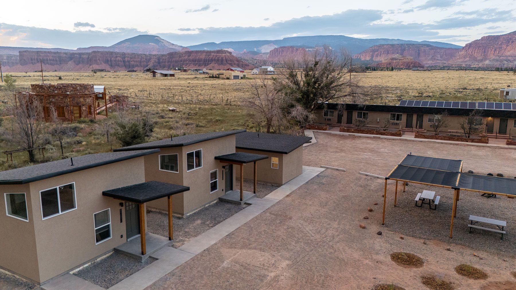 An aerial view of a house in the middle of a desert with mountains in the background.