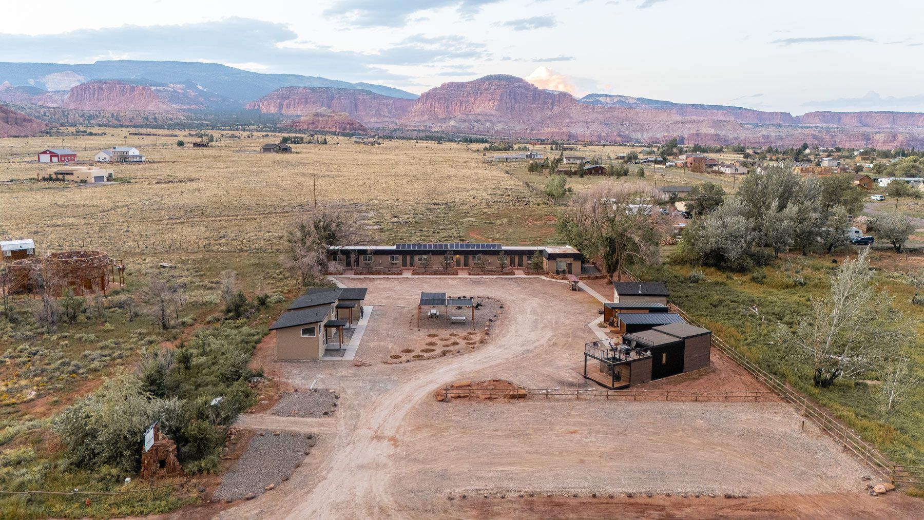 An aerial view of a house in the middle of a desert with mountains in the background.