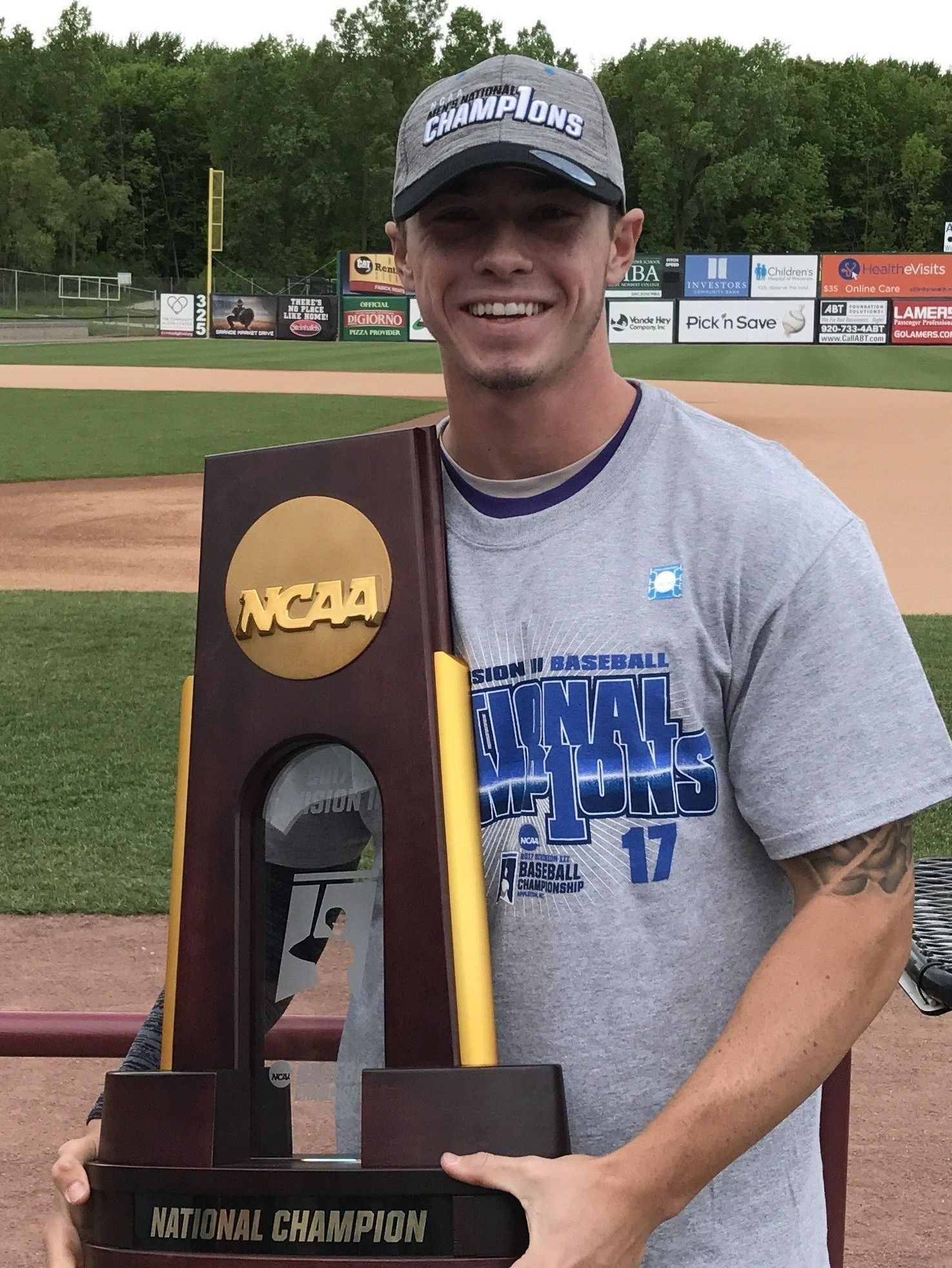 A man is holding a ncaa national championship trophy