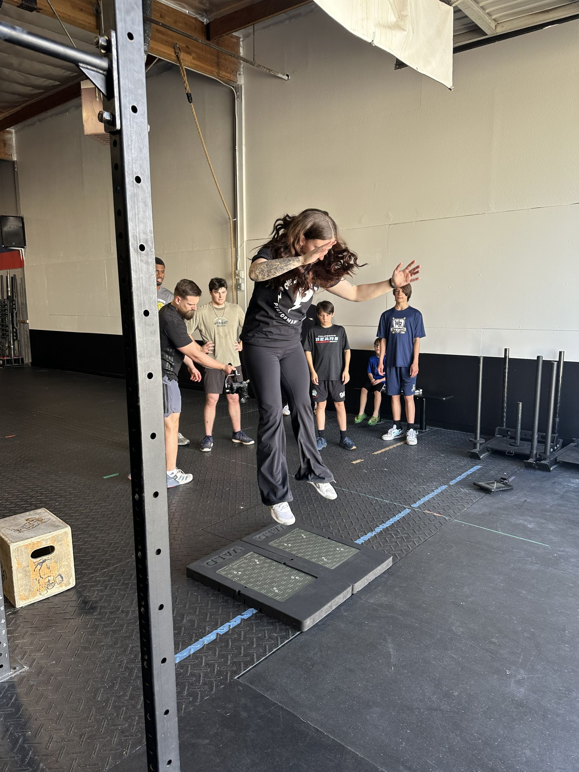 A man is flexing his muscles in a gym while another man looks on.