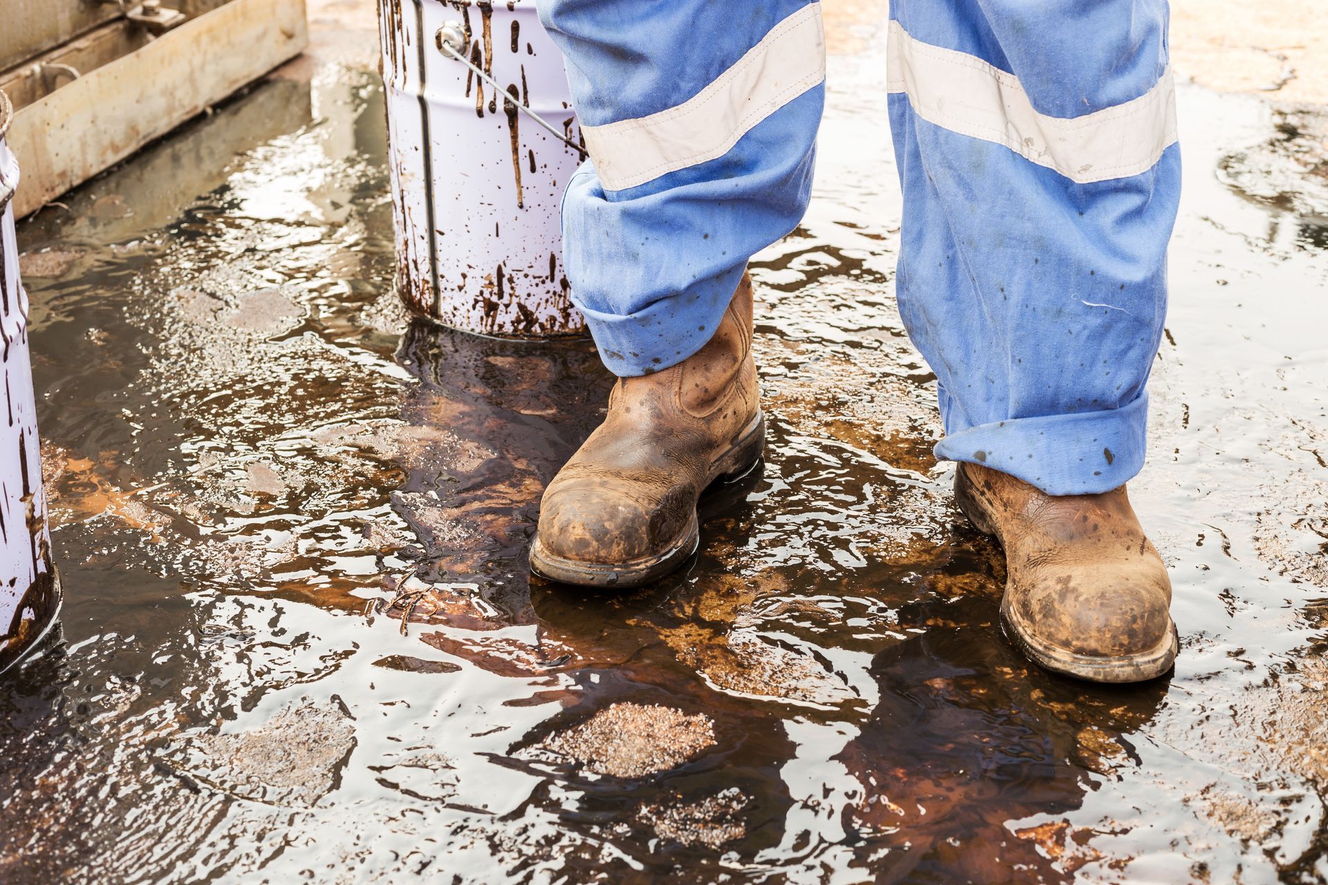 A person wearing safety boots is standing in a puddle of water.