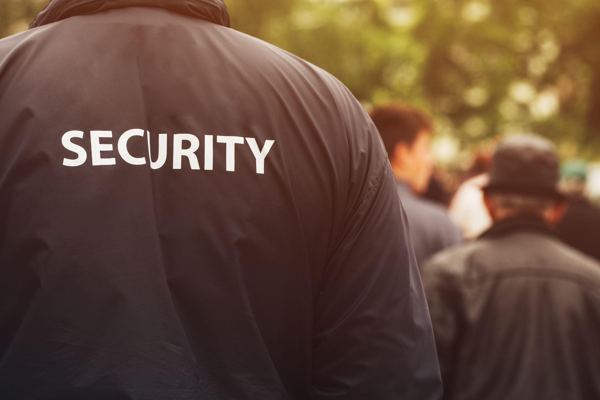 A security guard is standing in front of a crowd of people.