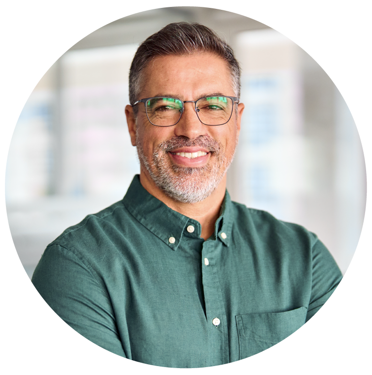 A man wearing glasses and a green shirt is smiling for the camera.