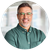 A man wearing glasses and a green shirt is smiling for the camera.