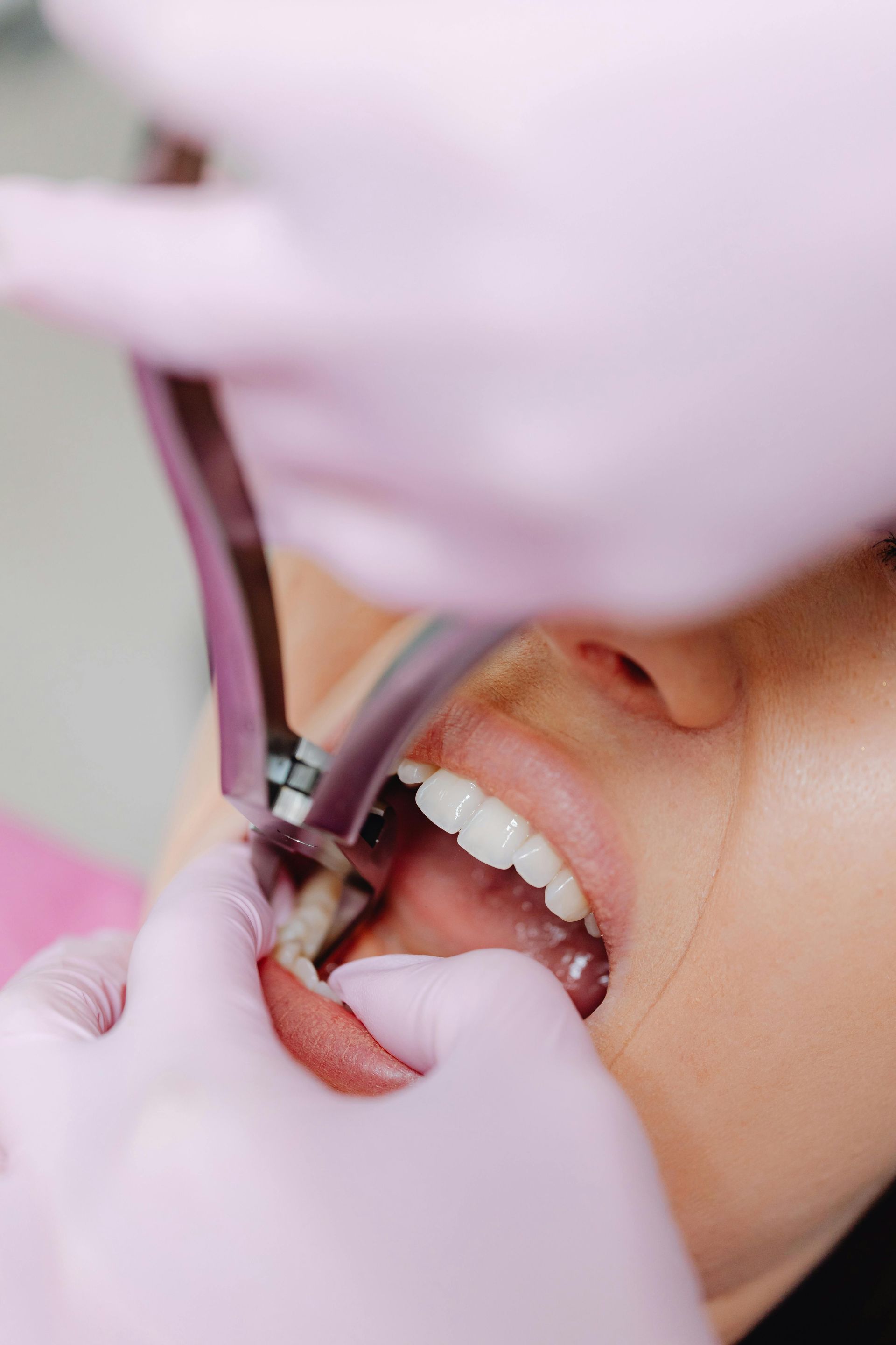 Woman smiling while holding a clear dental aligner to her teeth indoors