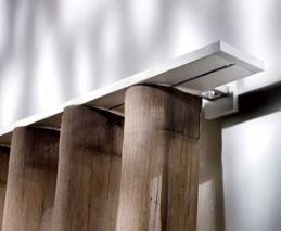 Primo piano di un binario per tende bianco sopra delle veneziane verticali in legno; un design moderno.