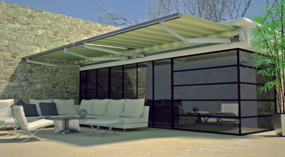 Moderno spazio abitativo all'aperto con tenda da sole retrattile, pareti in vetro e mobili bianchi.