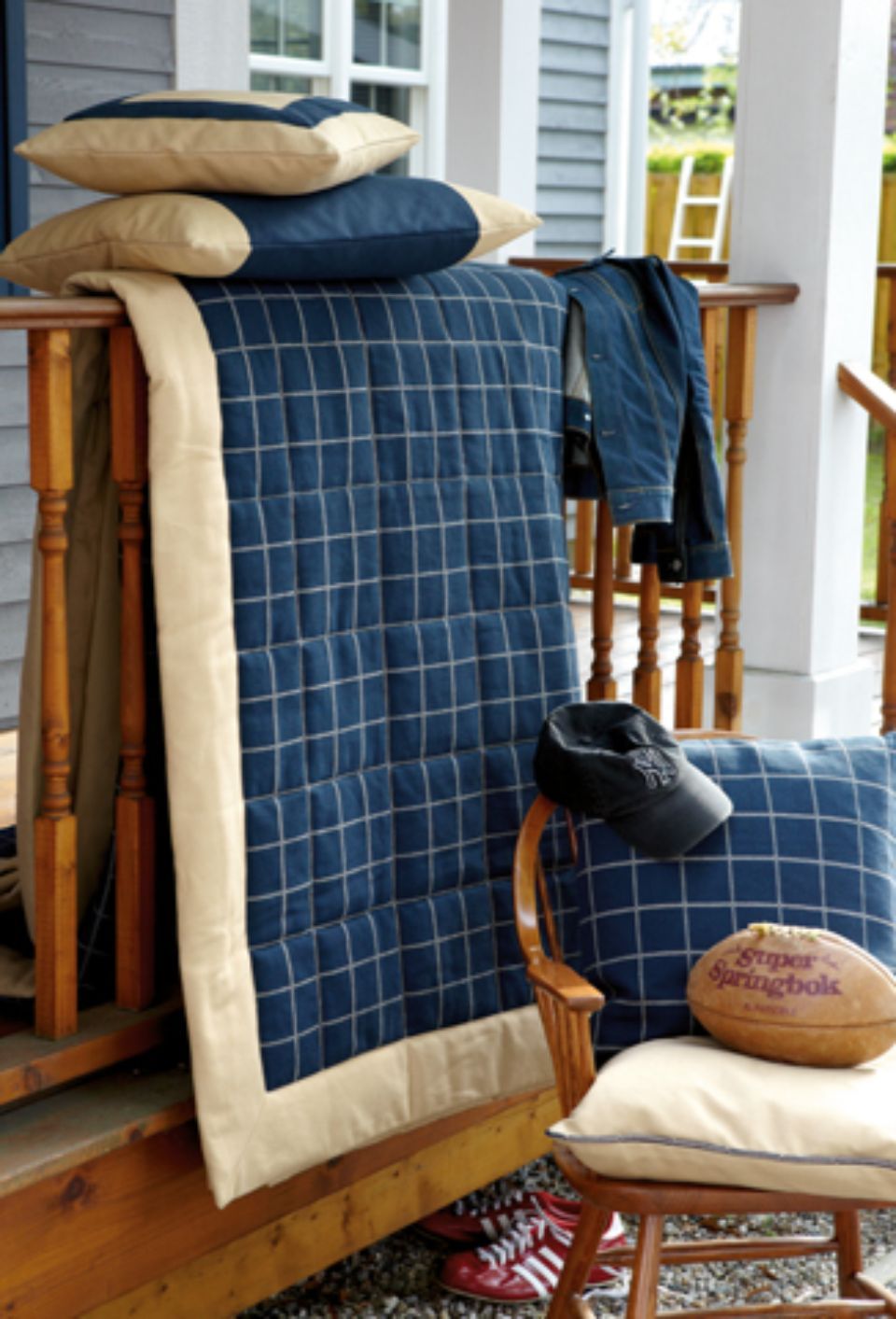 Decorazioni per il portico: trapunta a quadretti blu, cuscini, pallone da calcio, scarpe e una giacca.