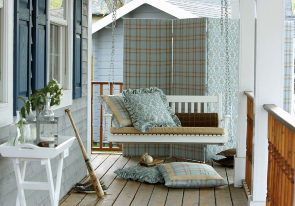 Altalena da veranda con cuscini e mazza da baseball su un portico in legno. Colori azzurro e marrone.