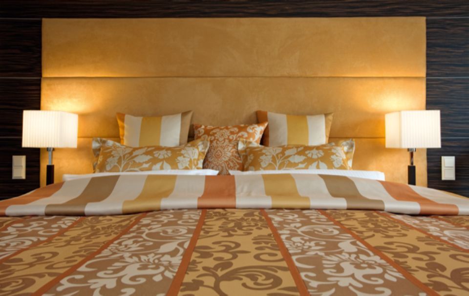 Lussuosa camera da letto con testiera dorata, biancheria da letto a righe e lampade.