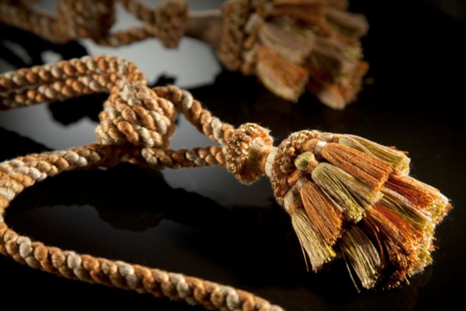 Corda con intreccio marrone e crema, annodata e terminante con una nappa a strati di fili marroni e beige.