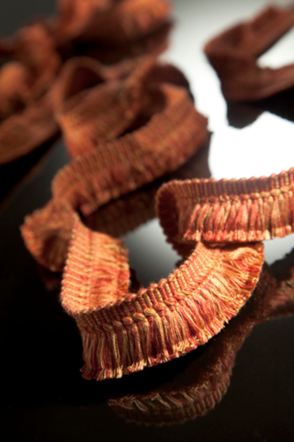 Bordi con frange marroni, arricciati su una superficie nera riflettente.