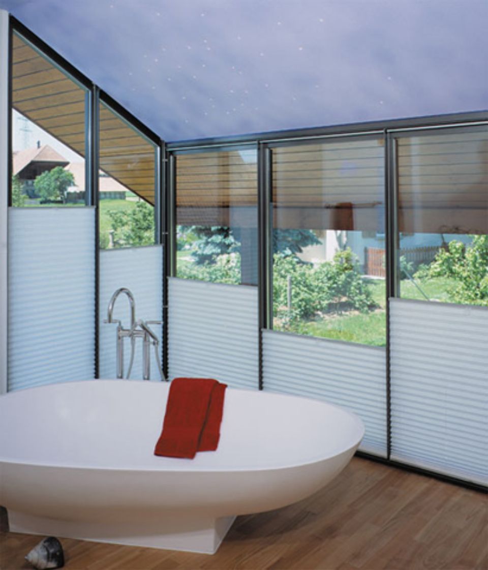 Bagno con vasca bianca, tende alla finestra e asciugamano rosso.