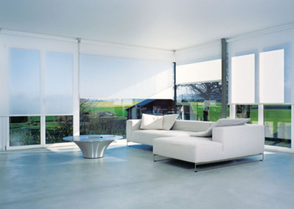 Moderno soggiorno bianco con ampie finestre, divano componibile e vista sul paesaggio.