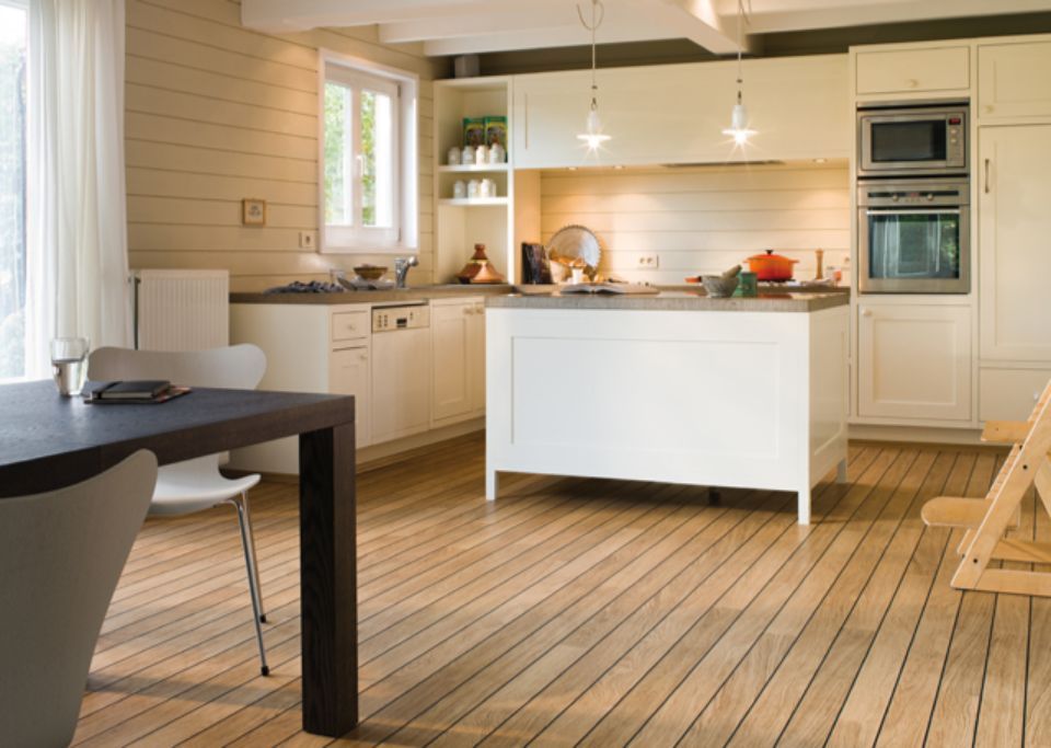 Una cucina luminosa con mobili bianchi, pavimento in legno e un tavolo da pranzo scuro.