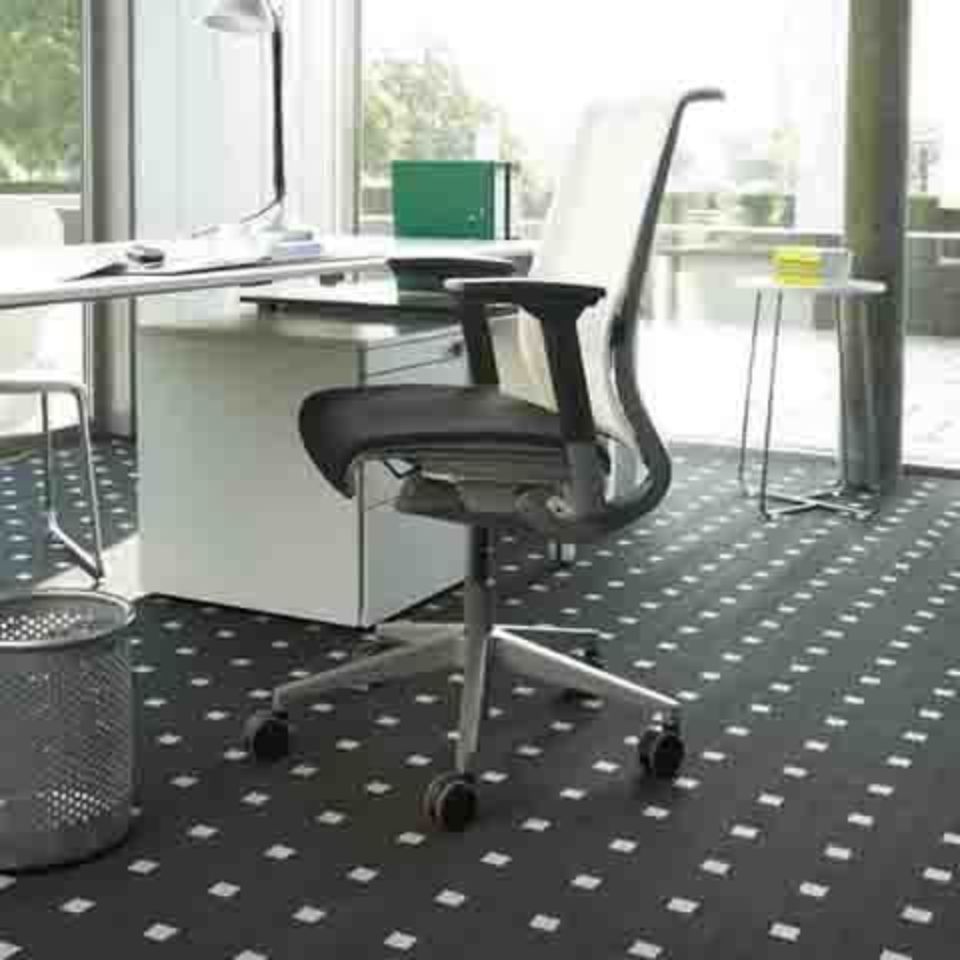 Ufficio con sedia, scrivania, computer e pavimento decorato in bianco e nero.