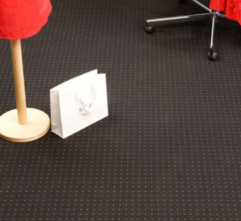 Sacchetto regalo bianco su un pavimento nero decorato, accanto a un oggetto rosso su un supporto di legno.