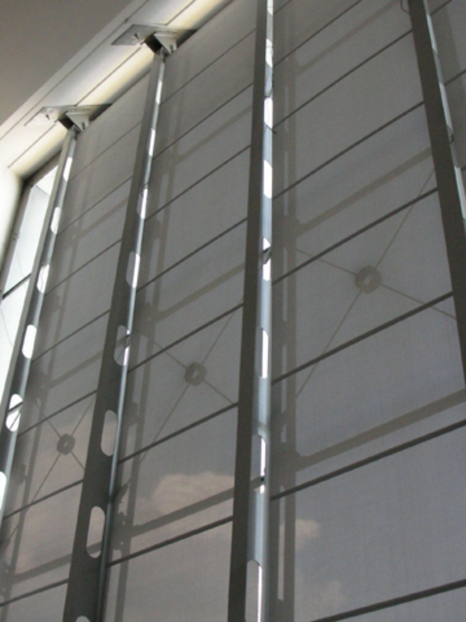 Parete bianca a griglia con supporti metallici verticali. La parete ha una finestra sul lato sinistro.