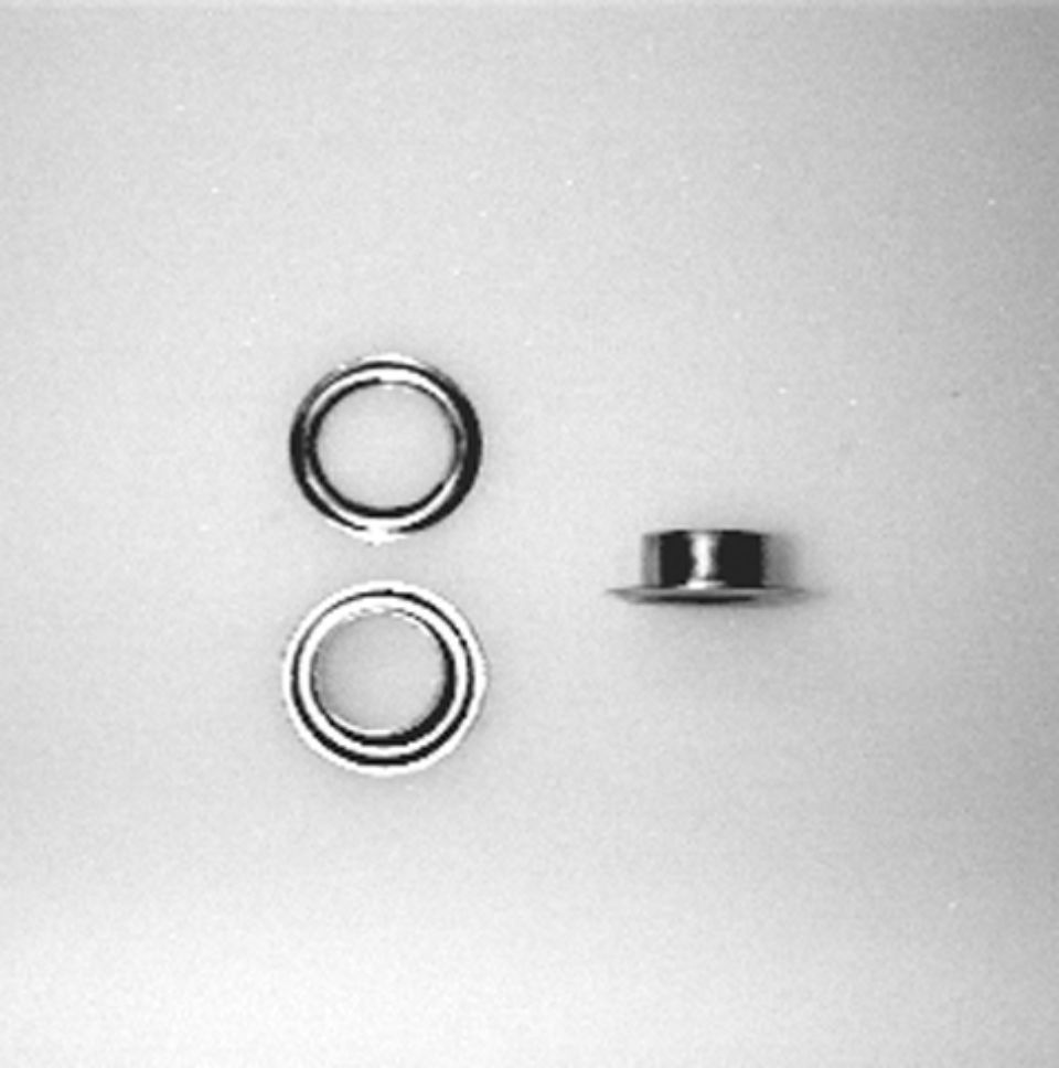 Tre occhielli argentati per il tessuto, due visti frontalmente, uno di lato.