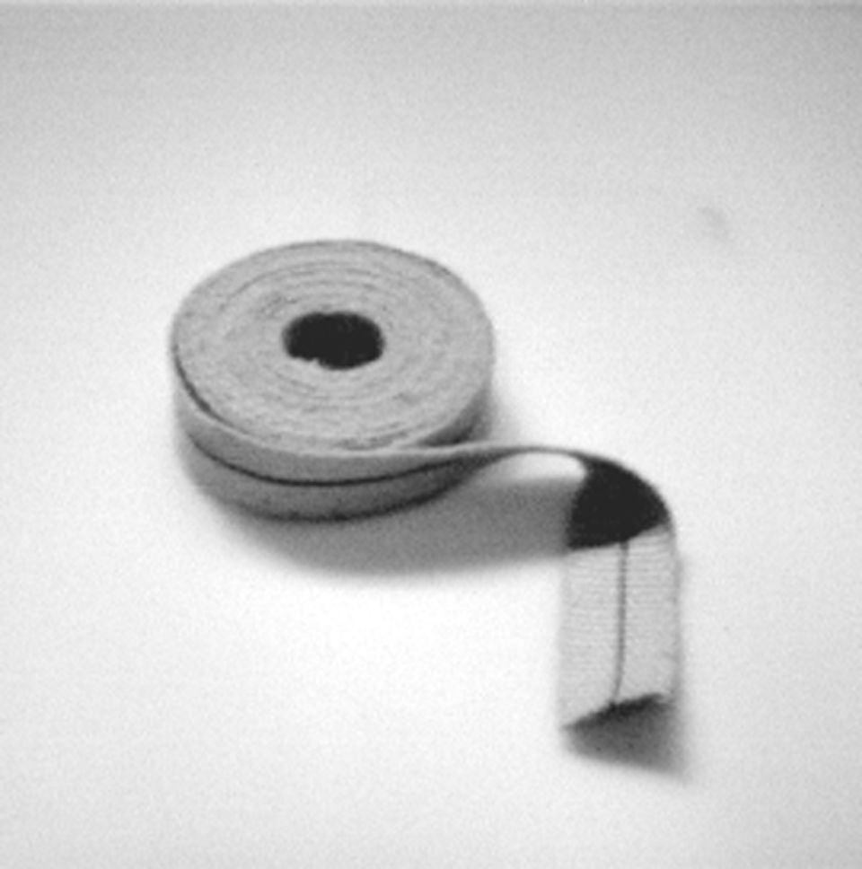 Un metro a nastro arrotolato, color marrone chiaro con segni neri, srotolato su una superficie chiara.