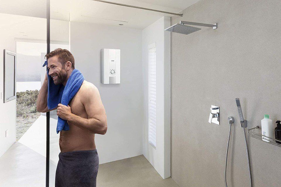 uomo che esce dalla doccia e scaldabagno sulla parete