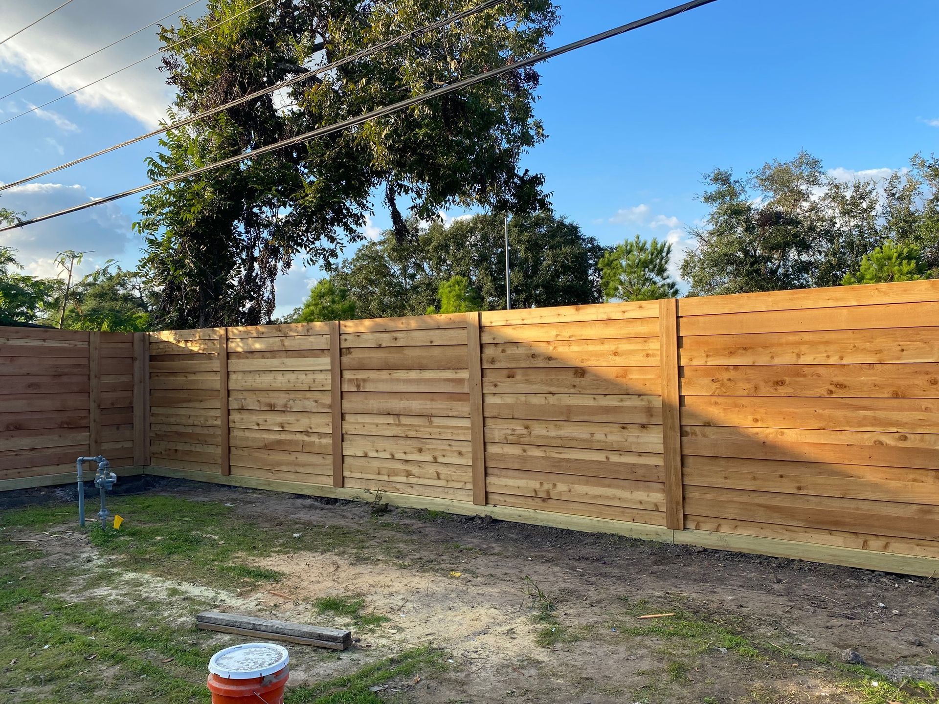 A wooden fence is in the backyard of a house.