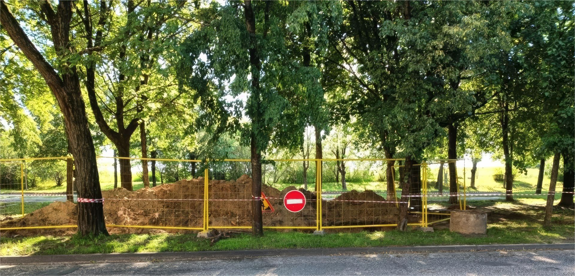 Roadside park entrance with red no-entry sign and wooden fence under trees