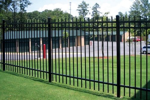 A black metal fence surrounds a lush green field.