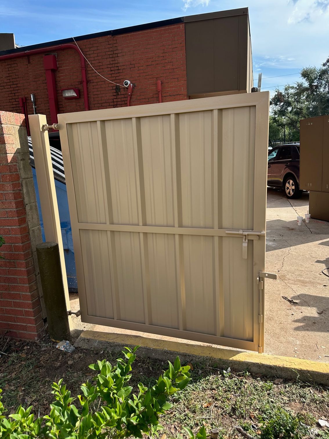 A sliding gate is open in front of a brick building.
