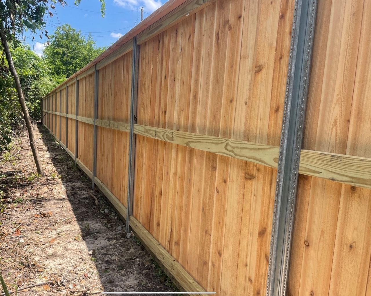 A wooden fence is sitting in the middle of a dirt field.