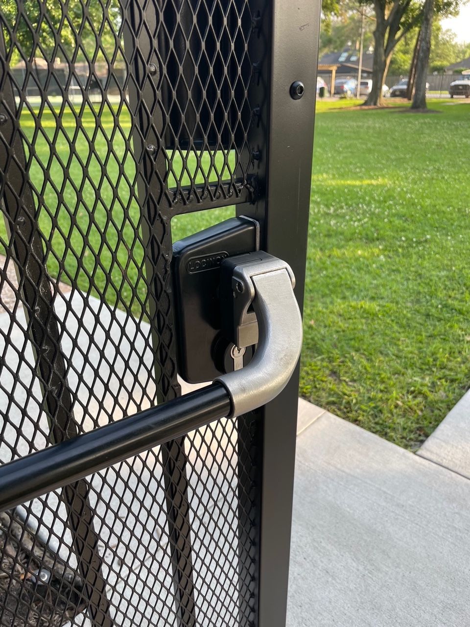 A close up of a metal gate with a handle in a park.