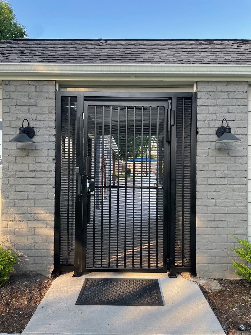 A black gate is sitting in front of a white brick building.