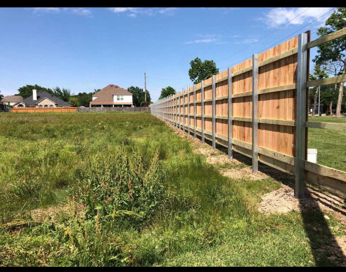 A wooden fence is sitting in the middle of a grassy field.