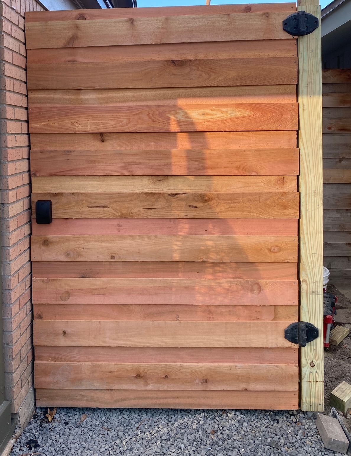 A wooden gate is sitting next to a brick wall.