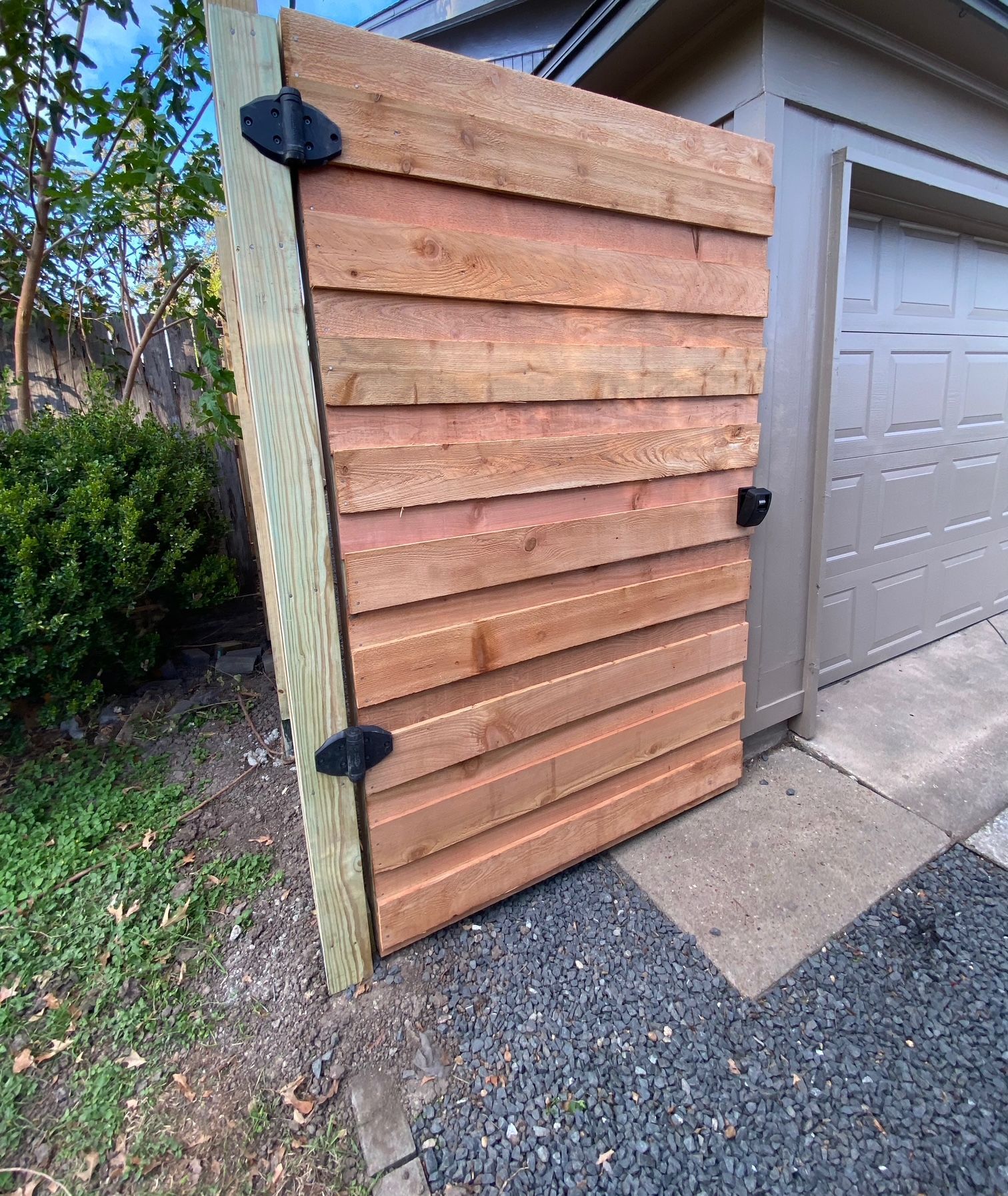 A wooden gate is sitting next to a garage door.