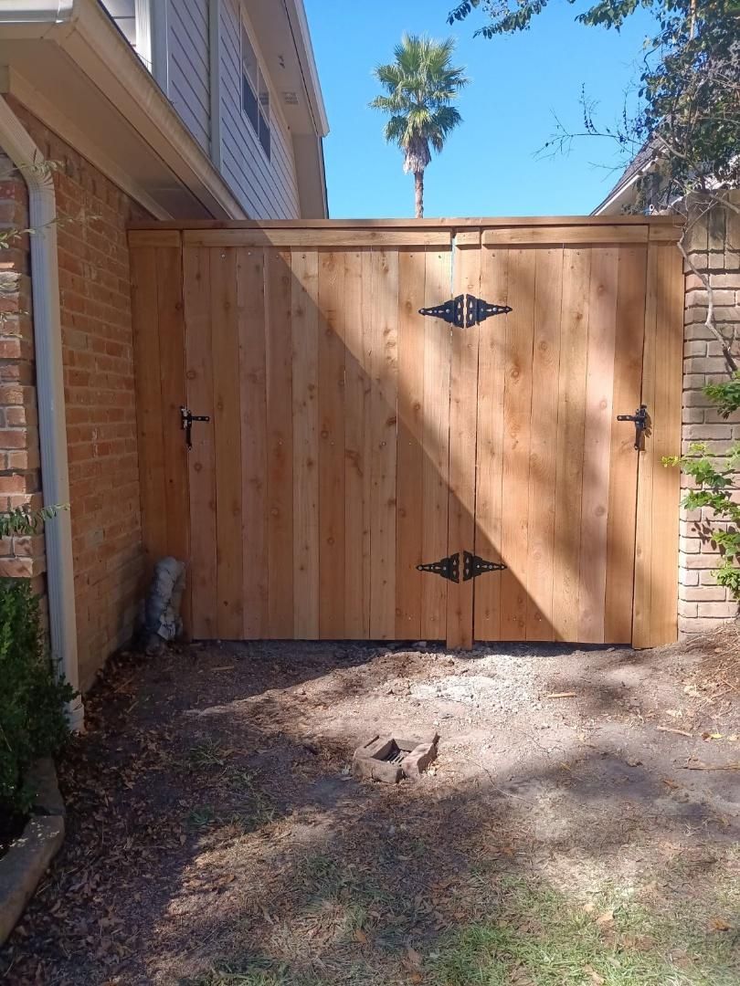 A wooden gate is sitting next to a brick building.