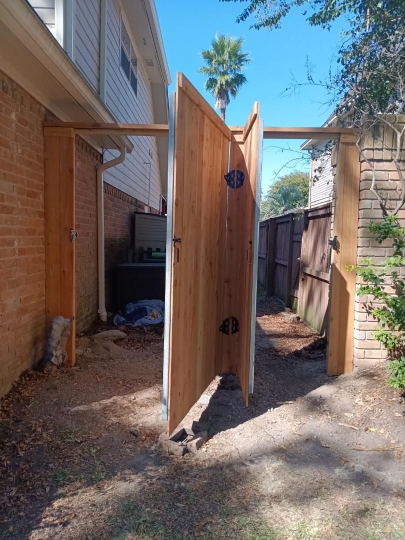 A wooden fence is being built in the backyard of a house.