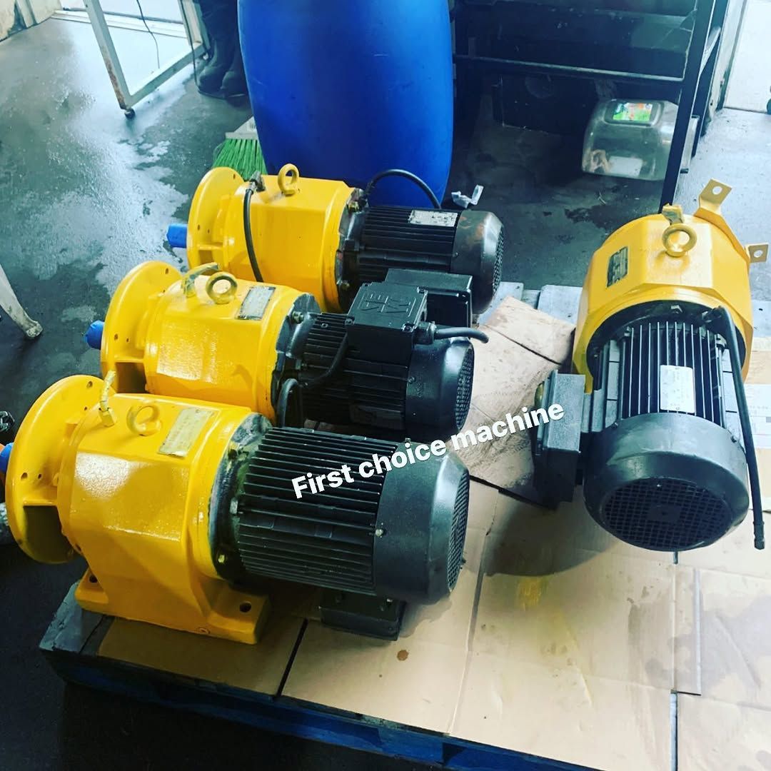Four industrial yellow electric motors with black fan housings sitting on a wooden pallet.
