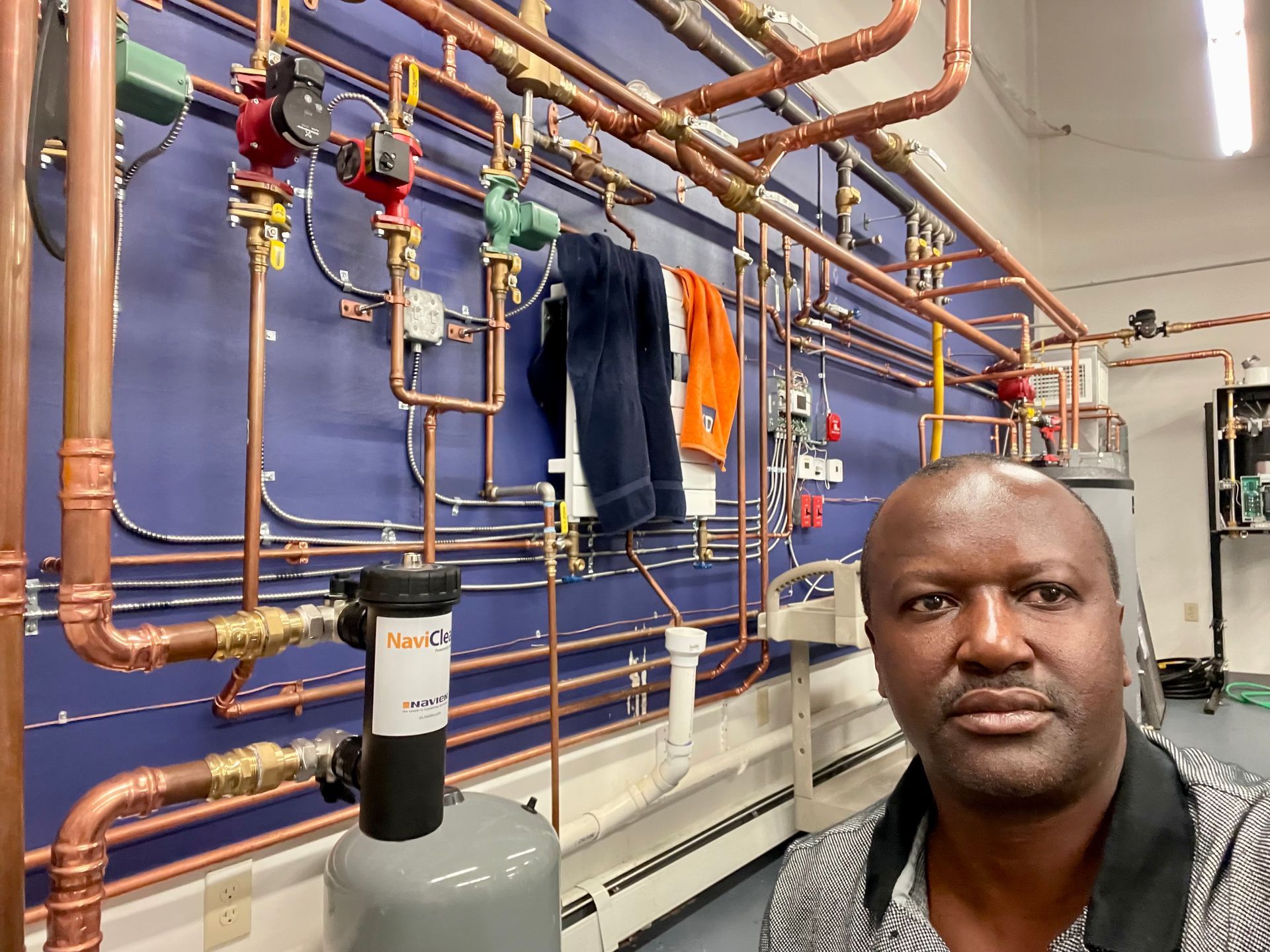 A man is standing in front of a wall of pipes.