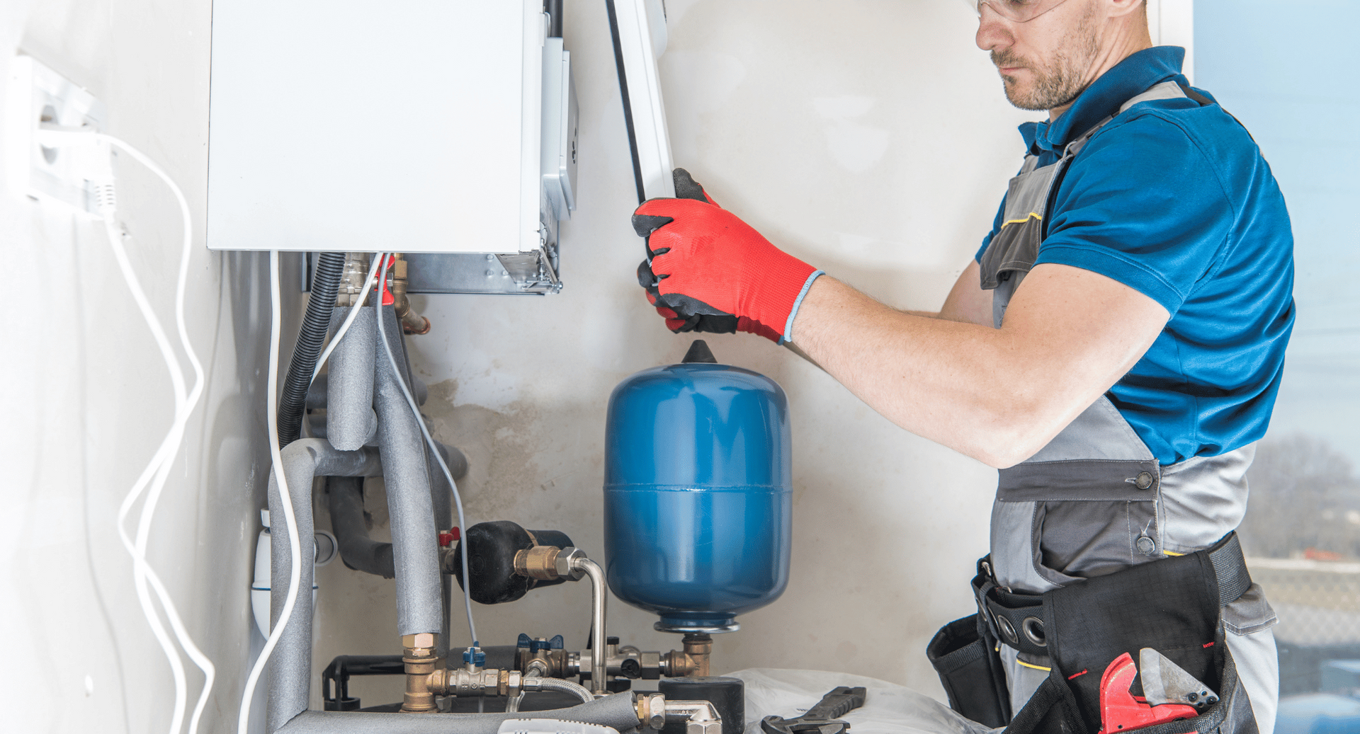 A man is working on a boiler in a room.