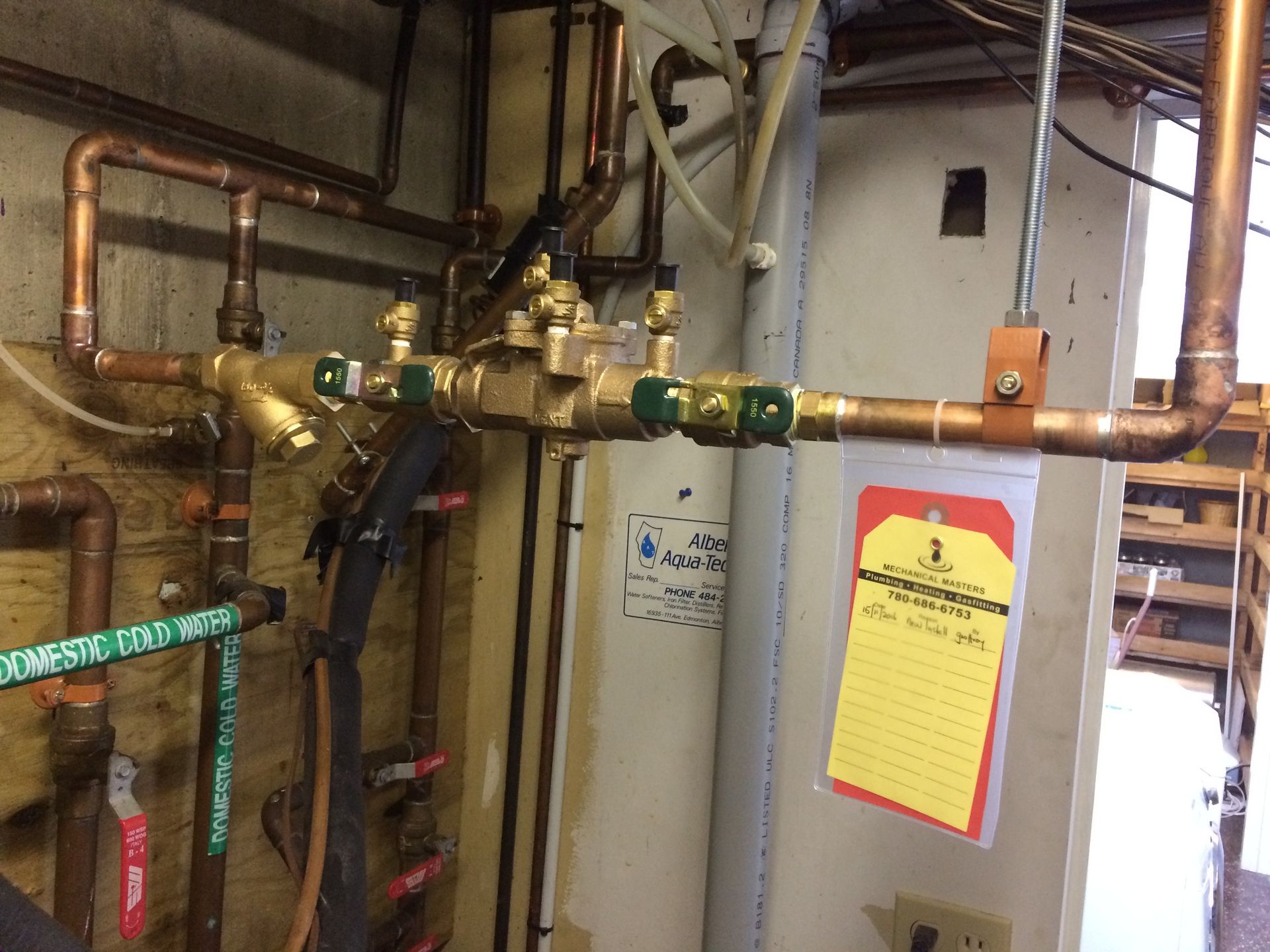 A room with a lot of pipes and a yellow tag on the wall.