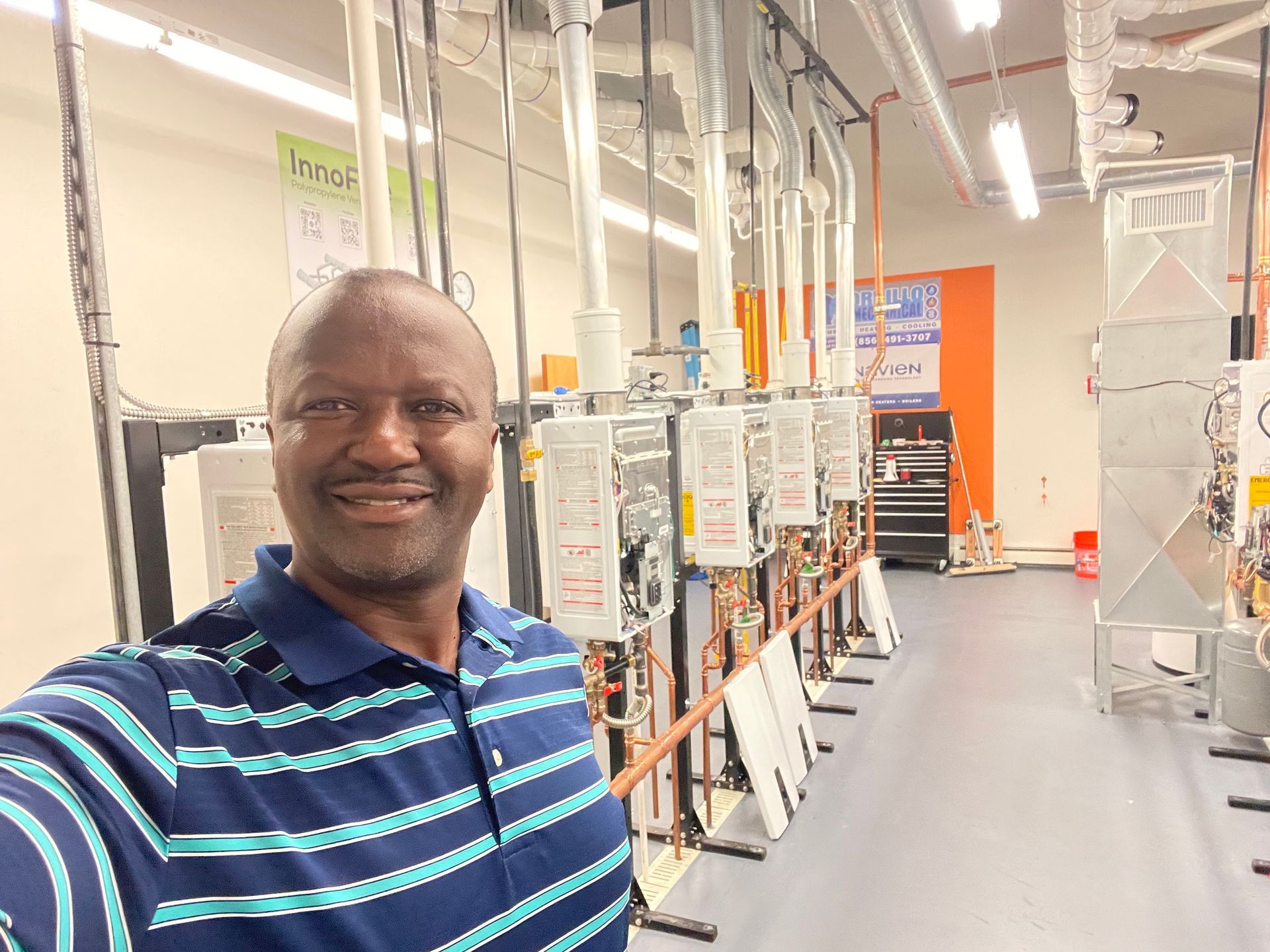A man is taking a selfie in a room with a lot of electrical equipment.